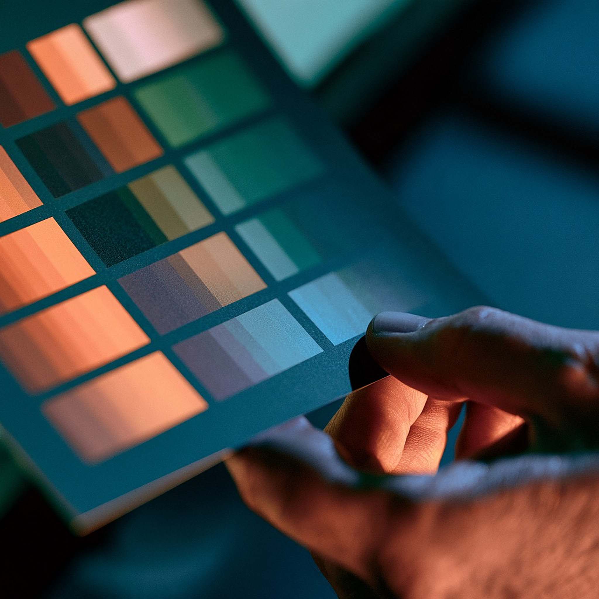 A hand holds a printed colour swatch card up for comparison.