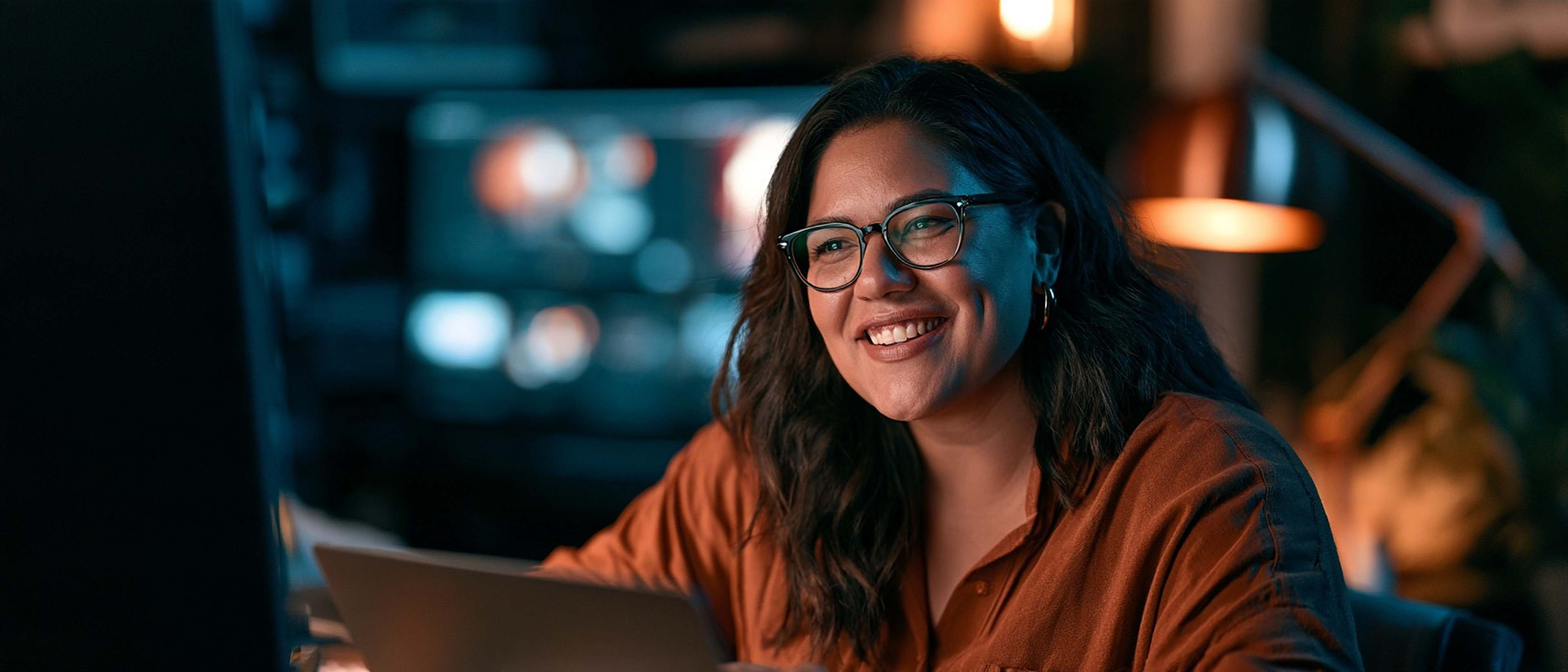 A producer smiles during a video call in a softly lit studio.